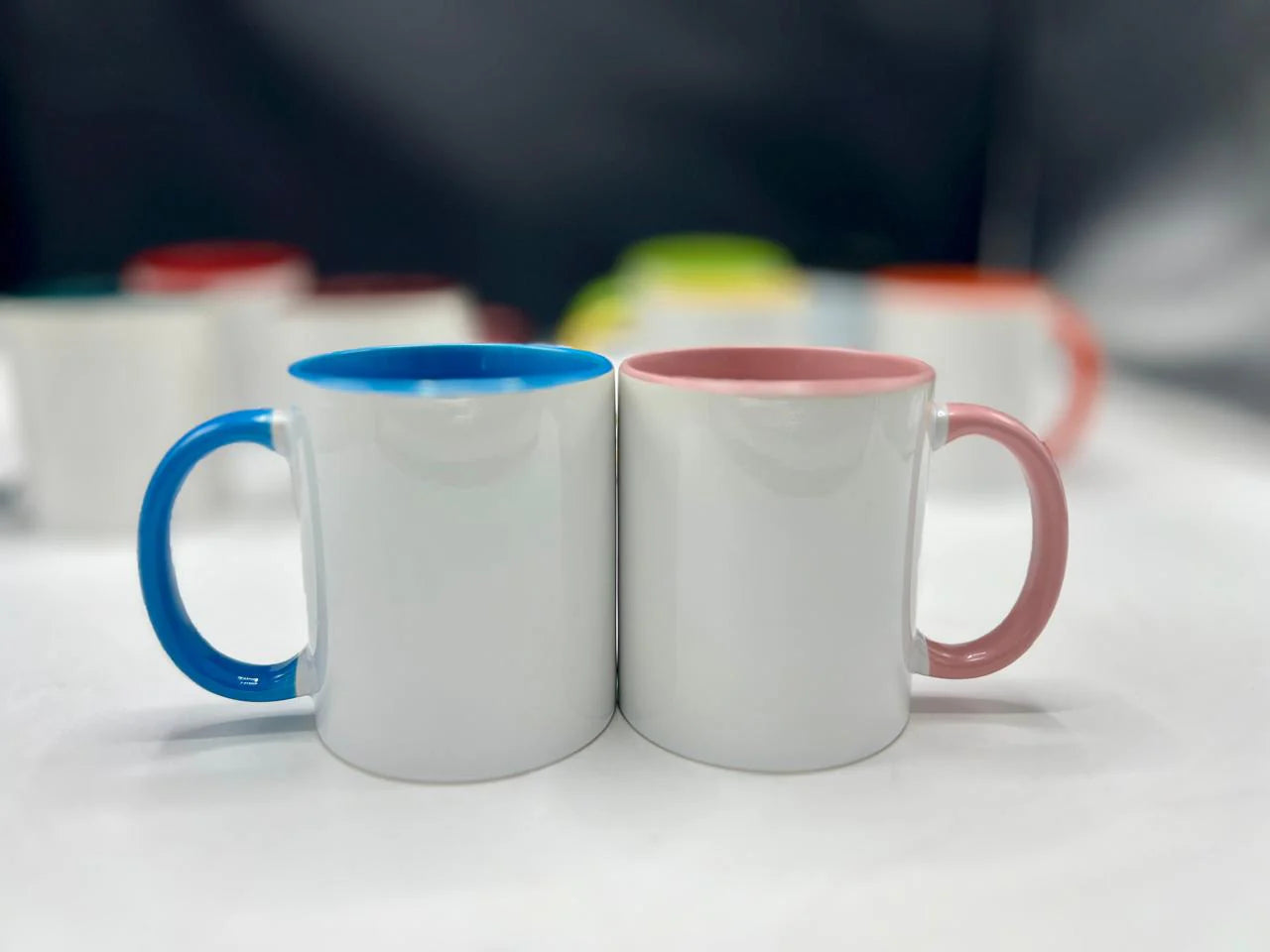 Two mugs with blue and pink interior colors on a white surface.