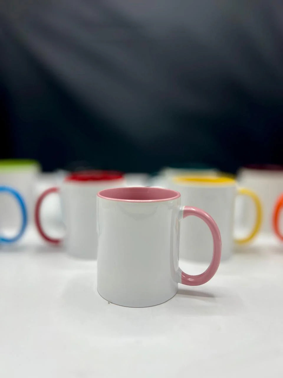 White mug with pink handle and interior on a white surface with blurred background