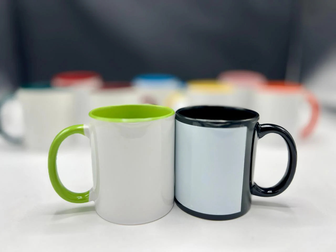 Two mugs, one with a green interior and white exterior, and the other with a black interior and white exterior, on a light surface.