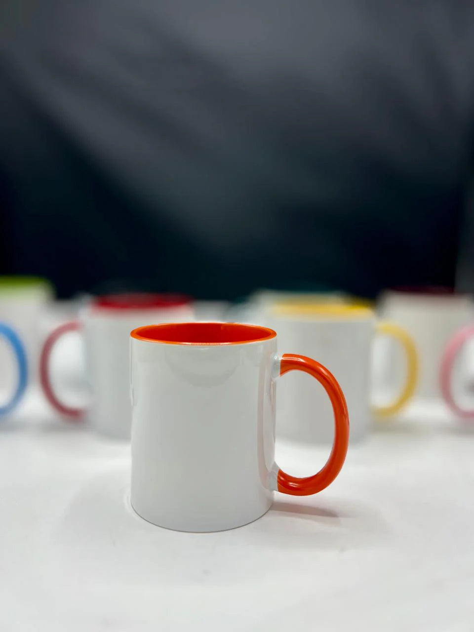 White mug with an orange handle on a white surface