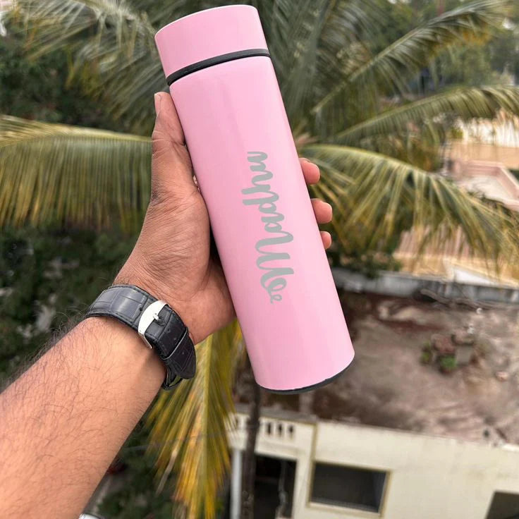 Hand holding a pink water bottle with 'my bottle' text against a palm tree background