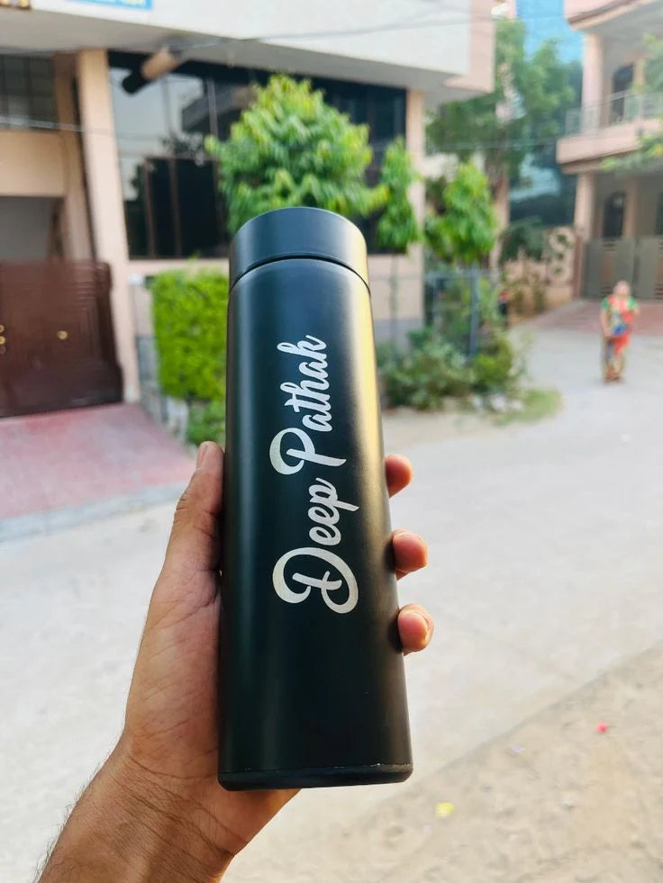Black water bottle with 'Deep Pathak' branding held by a hand outdoors.