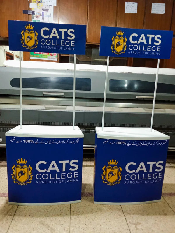 Two promotional stands for CATS College with branding in a indoor setting.