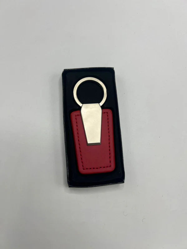 Red leather key fob with gold accent in a black box on a gray background